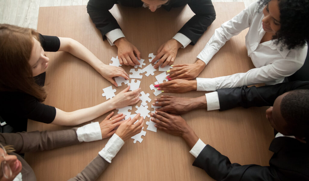 Des collaborateurs rassemblés autour d’un puzzle pour symboliser l’intelligence collective et la coopération